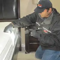 Bed bug inspection technician checking a mattress and bed frame for signs of infestation in Dallas, TX
