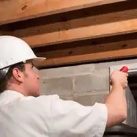 Termite inspection technician checking a basement wall and framing for termite activity in Dallas, TX